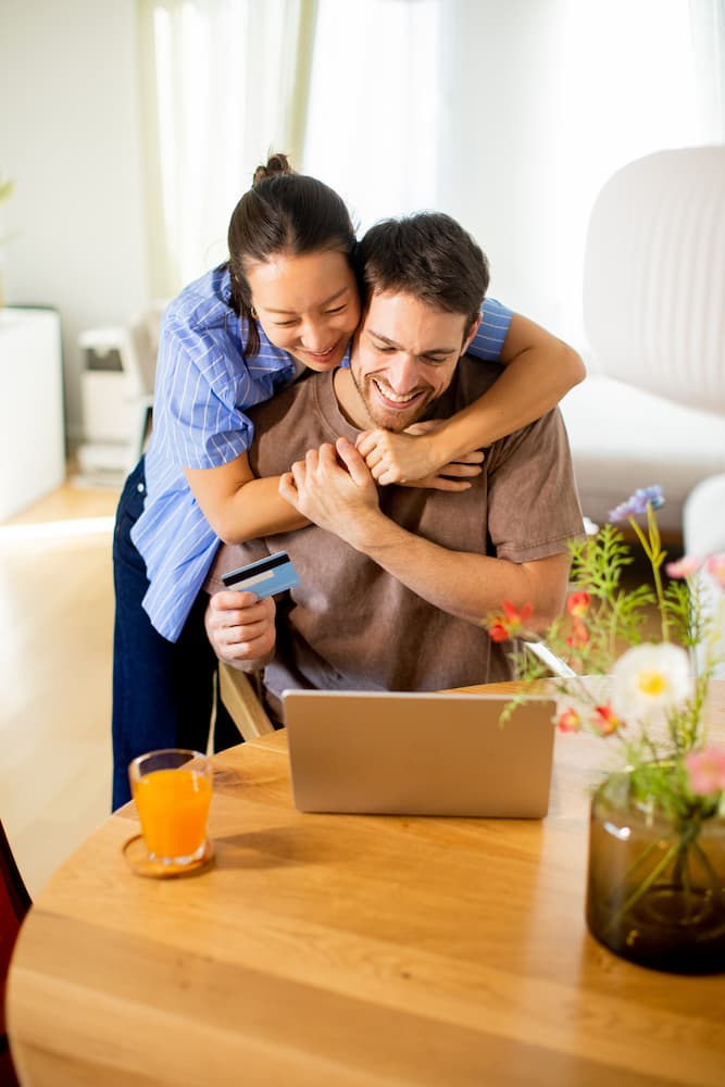 Paar sitzt am Tisch und schließt einen neuen Stromtarif am Laptop ab
