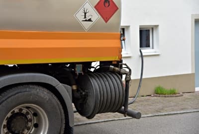 Tankwagen liefert Heizöl über Schlauch an ein Wohnhaus